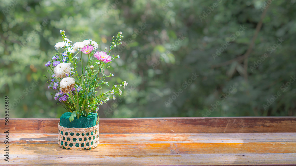 Flowers in a basket placed on a wooden table with natural sunlight spreading thin and copy space. Flowers in a basket placed on a wooden table with natural sunlight spreading thin and copy space.