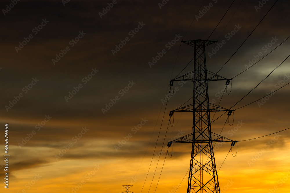 A large high-voltage electricity pole made of steel with a backdrop in the color of the sky before sunset.