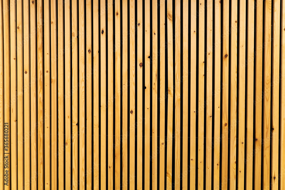 Vertical thin wooden slats on wall in modern interior. Natural brown color - obrazy, fototapety, plakaty 