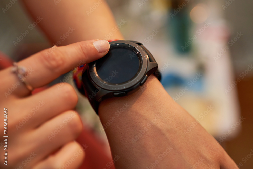 Top view of female hands setting smart watch. Close up of woman hands using smartwatch. Dramatic ambient light, golden hour.