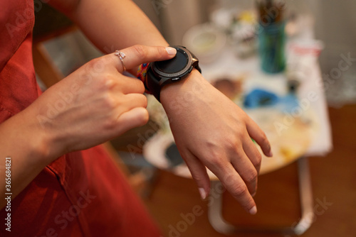 Top view of female hands setting smart watch. Close up of woman hands using smartwatch. Dramatic ambient light, golden hour. © mercankaya