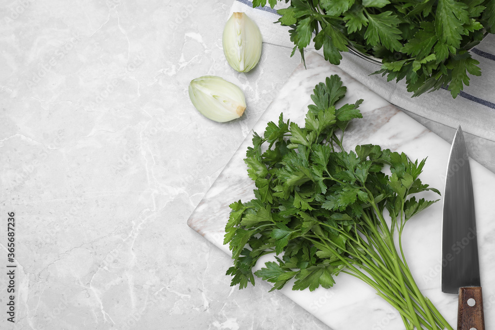 Marble board with fresh green parsley and knife on grey table, flat lay. Space for text Marble board with fresh green parsley and knife on grey table, flat lay. Space for text