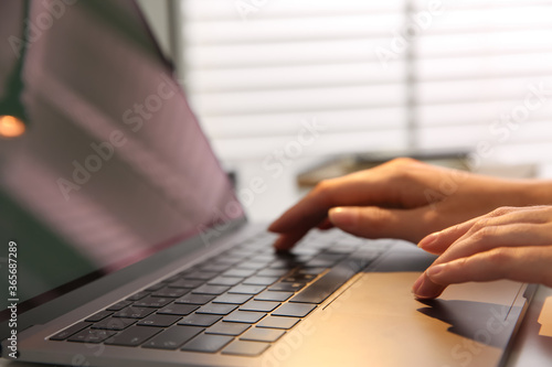 Woman working with modern laptop indoors, closeup