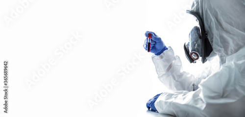 Lab technician holding blood tube test in the research laboratory. Scientist in personal protective equipment suit or ppe working. Health care, medical and science concept.