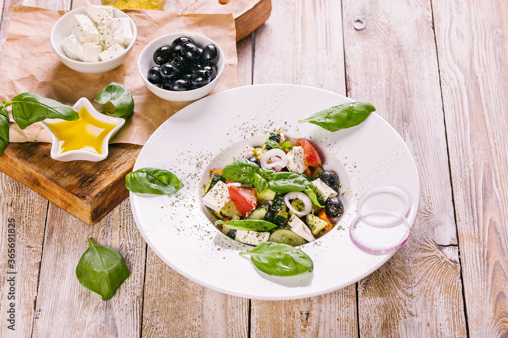 Greek salad in a white plate. Mediterranean vegetable salad with fresh basil, olives, olive oil and spices. Close-up