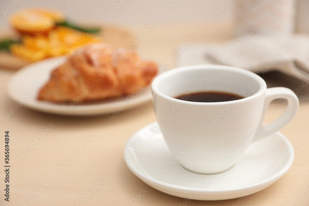 Cup of hot aromatic coffee and tasty croissant on table Cup of hot aromatic coffee and tasty croissant on table