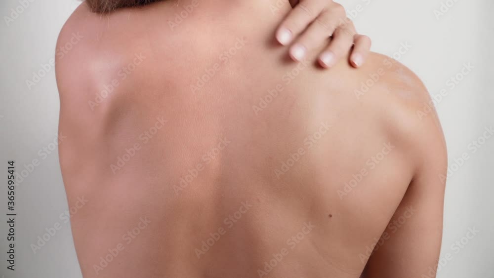 View from back young slim woman applying cream on her shoulder on white background. Beautiful girl apply body lotion. Health and beauty concept View from back young slim woman applying cream on her shoulder on white background. Beautiful girl apply body lotion. Health and beauty concept