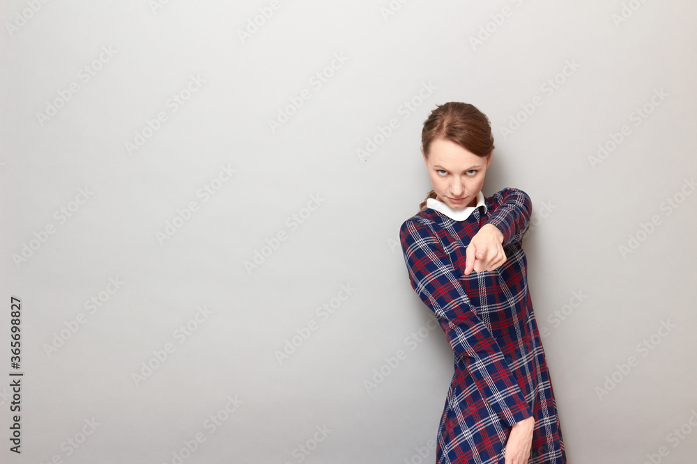 Portrait of serious girl pointing with index finger at you Portrait of serious girl pointing with index finger at you