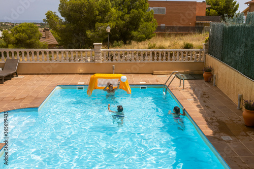 Three kids playing with a ball on a pool