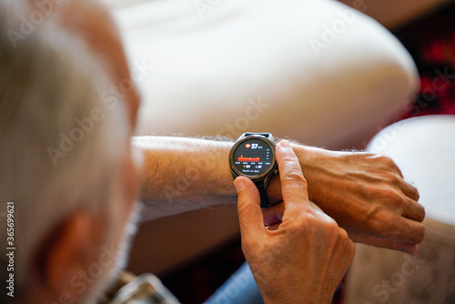 old white haired man using smart watch checking his cardiogram ecg
