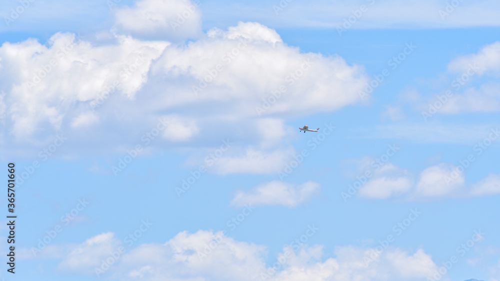 Small airplane flies among the white clouds on the blue sky Small airplane flies among the white clouds on the blue sky