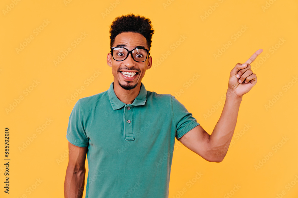 Handsome african boy in big glasses expressing amazement. Indoor shot of emotional male model with black curly hair. Handsome african boy in big glasses expressing amazement. Indoor shot of emotional male model with black curly hair.