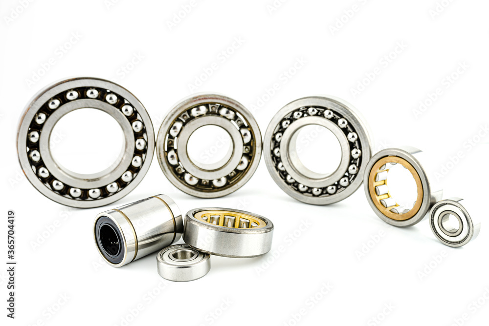 Background made of several ball bearings, isolated on a white background, selective focus, in the background the bearings standing in a row. Background made of several ball bearings, isolated on a white background, selective focus, in the background the bearings standing in a row.