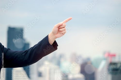 Hand of businessman pointing to the sky with city bokeh lights and skyscraper, heading to the future concept