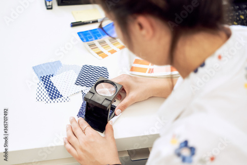 Female fashion designer holding color samples choosing fabric textile at workplace, dressmaker or tailor checking fabric quality, close up view