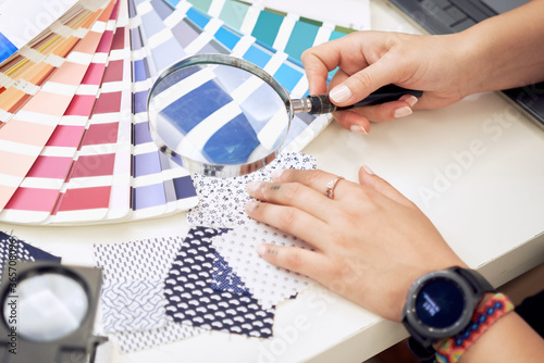 Female fashion designer holding color samples choosing fabric textile at workplace, dressmaker or tailor checking fabric quality, close up view