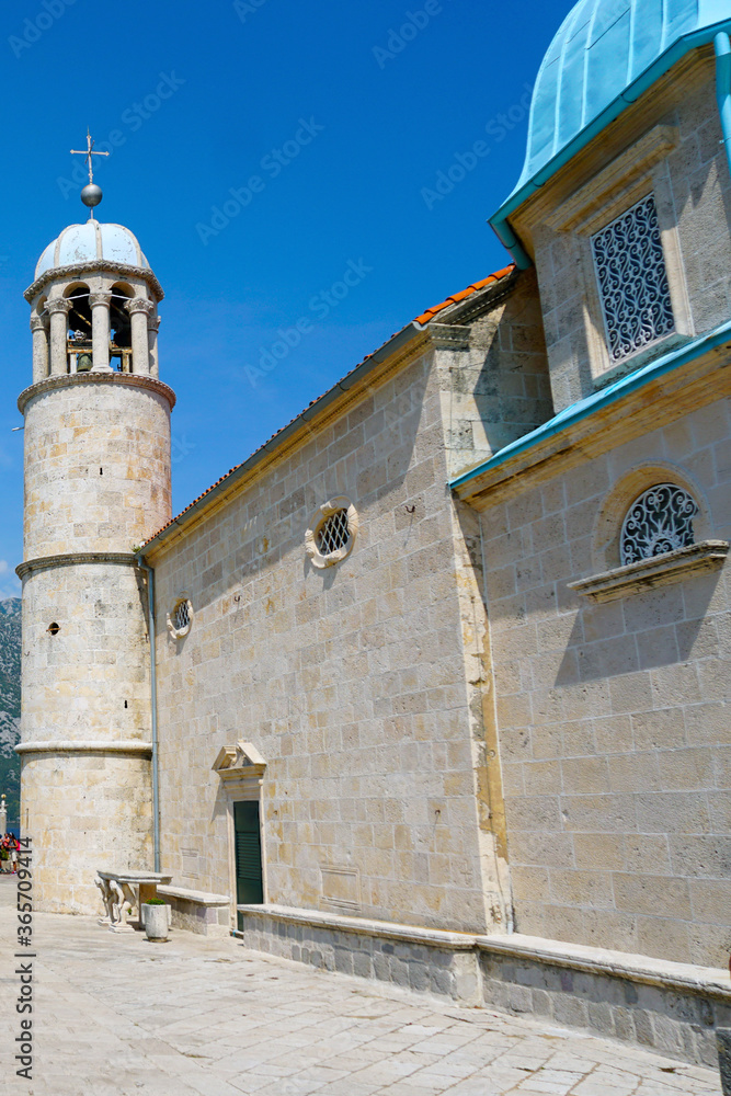 Fototapeta premium The blue dome and bell tower of the Temple of the Lady of the Rock on a background of blue sky. Island near Perast. Montenegro.