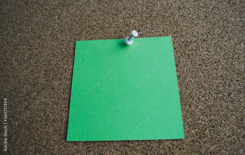 Close up of a green paper note on a cork Board, attached with a white pushpin. Copy space Close up of a green paper note on a cork Board, attached with a white pushpin. Copy space
