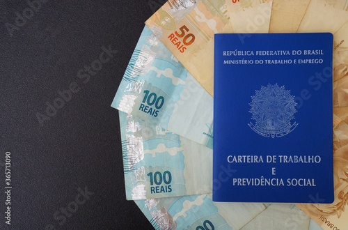 Brazilian work card (carteira de trabalho) and Brazilian money on black background. Work concept. 
