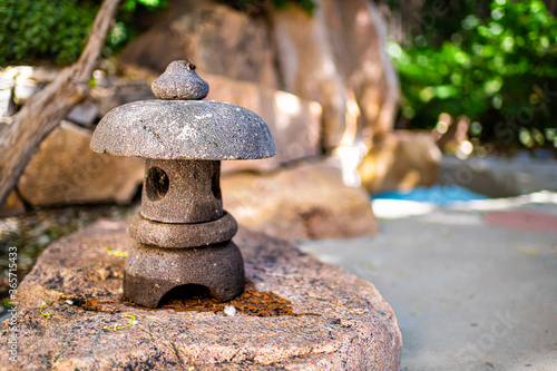 Japanese spa stone lantern closeup of zen garden in Japan onsen with blue pool cold plunge in blurry background