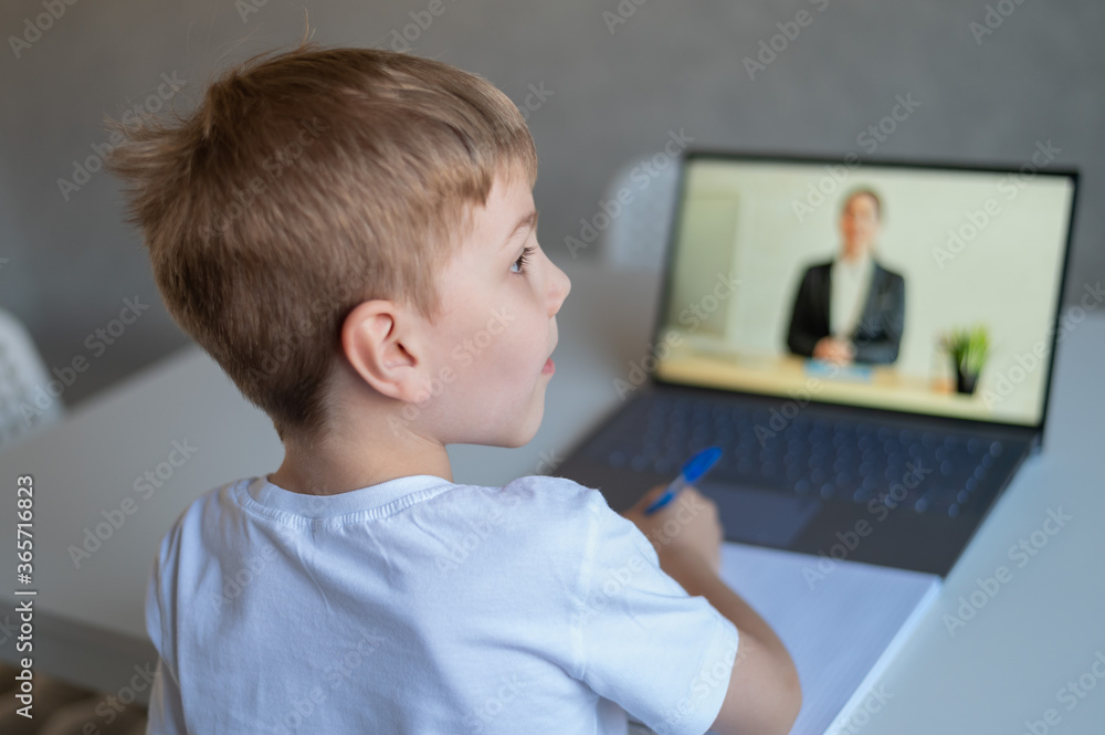 The boy communicates with a female teacher on a laptop webcam. Online lesson. Distance education in quarantine. A schoolboy is studying at home in the epidemic of coronavirus. The boy communicates with a female teacher on a laptop webcam. Online lesson. Distance education in quarantine. A schoolboy is studying at home in the epidemic of coronavirus.