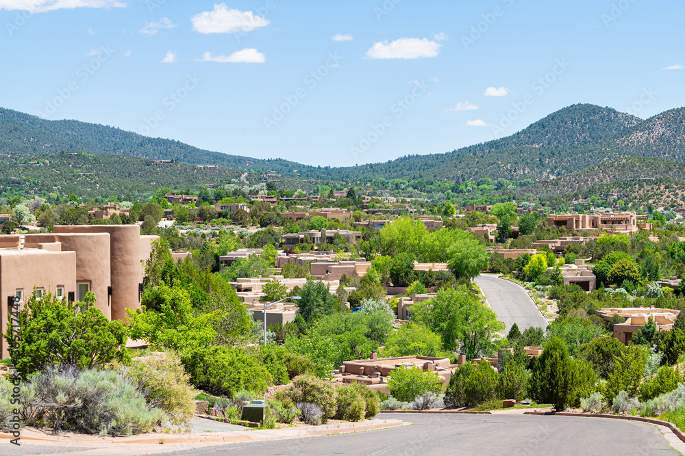 Naklejka premium Widok na panoramę miasta w Santa Fe w Nowym Meksyku w górach drogi przez sąsiedztwo społeczności z zielonymi roślinami latem i tradycyjnymi domami adobe