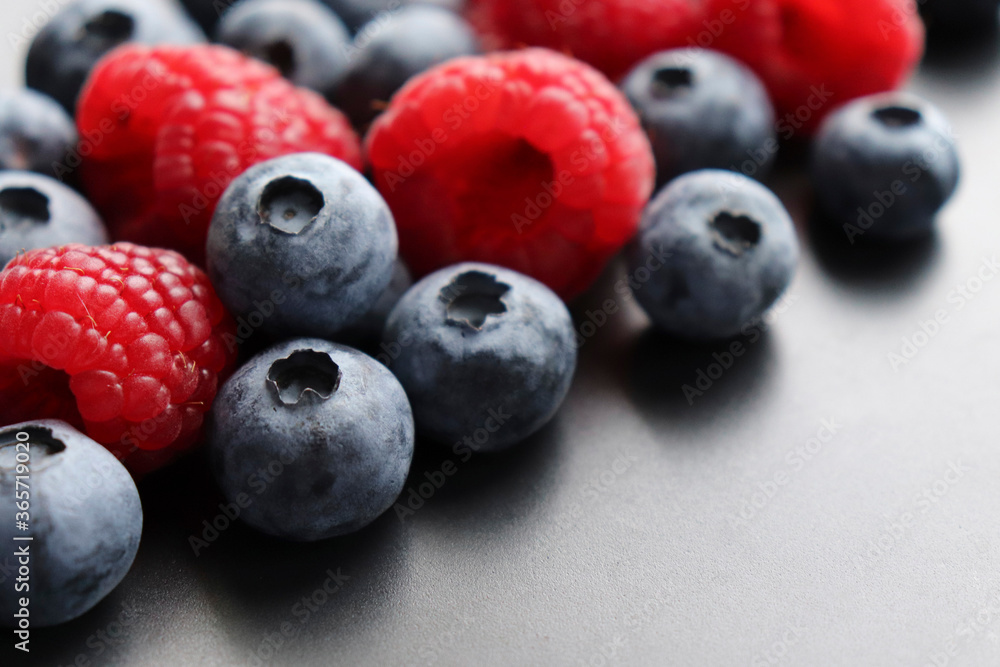 Background with ripe and bright raspberries and blueberries. Berry mix. Heart-shaped raspberries. Proper and healthy nutrition. Design for advertising and books of juices, jams, dessert. Ingredient. Background with ripe and bright raspberries and blueberries. Berry mix. Heart-shaped raspberries. Proper and healthy nutrition. Design for advertising and books of juices, jams, dessert. Ingredient.