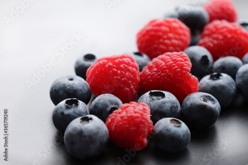 Background with ripe and bright raspberries and blueberries. Berry mix. Heart-shaped raspberries. Proper and healthy nutrition. Design for advertising and books of juices, jams, dessert. Ingredient.