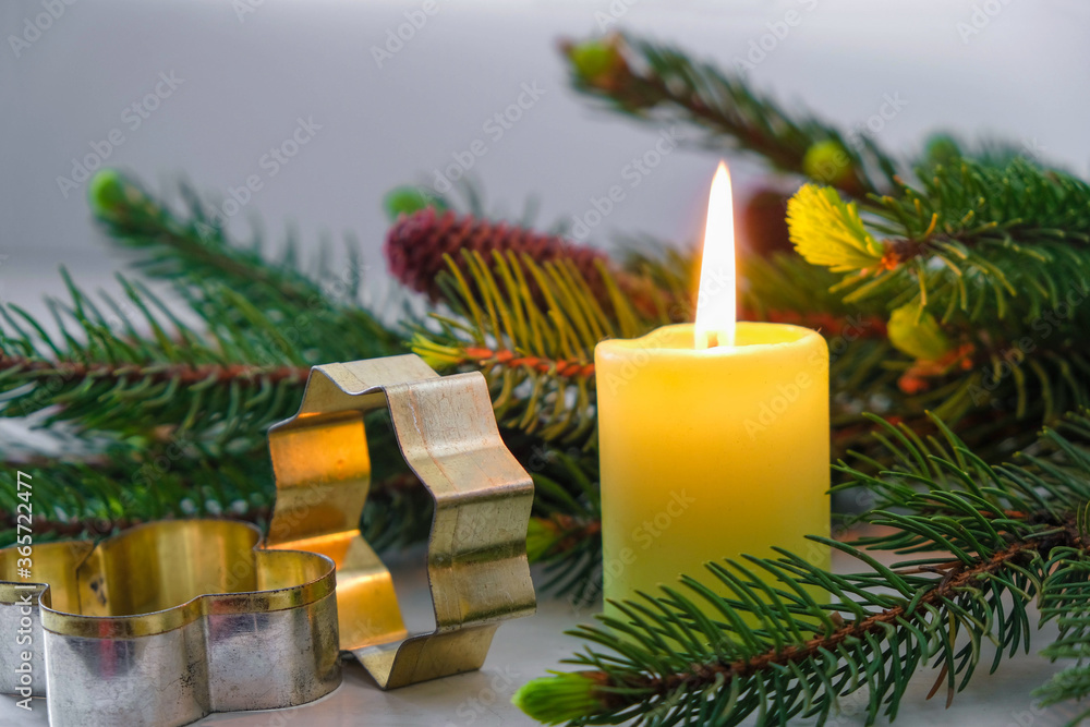 Spruce branch , Christmas burning candle and metal cookie cutters on a gray background. Home Christmas concept.