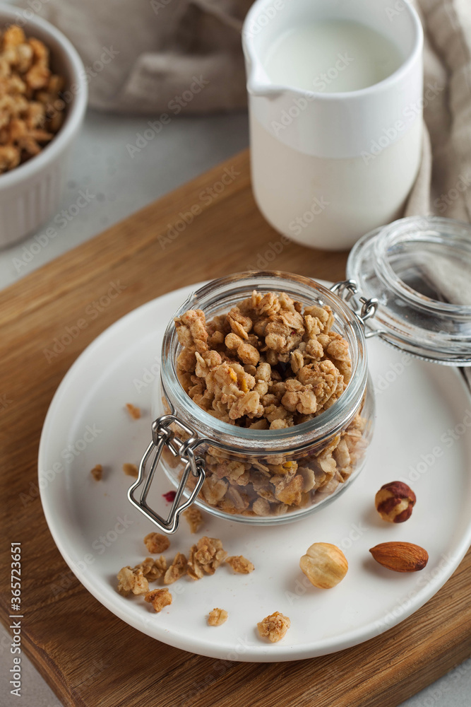 homemade granola with nuts in a glass jar on a wooden board. healthy breakfast concept, vegetarian breakfast. homemade granola with nuts in a glass jar on a wooden board. healthy breakfast concept, vegetarian breakfast.