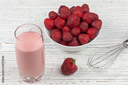 strawberry cocktail, blender and plate with strawberries on a white wooden background