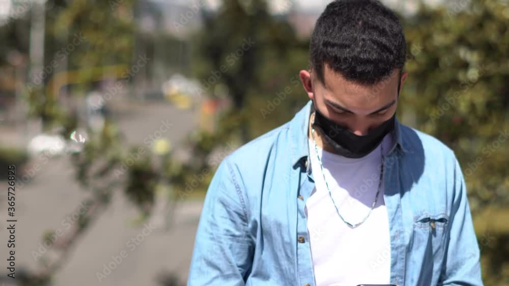 Time-lapse de joven caucasico con tapa bocas revisa su celular, mirando las redes sociales. En tiempo de cuarentena. Covid-19 al aire libre. Time-lapse de joven caucasico con tapa bocas revisa su celular, mirando las redes sociales. En tiempo de cuarentena. Covid-19 al aire libre.