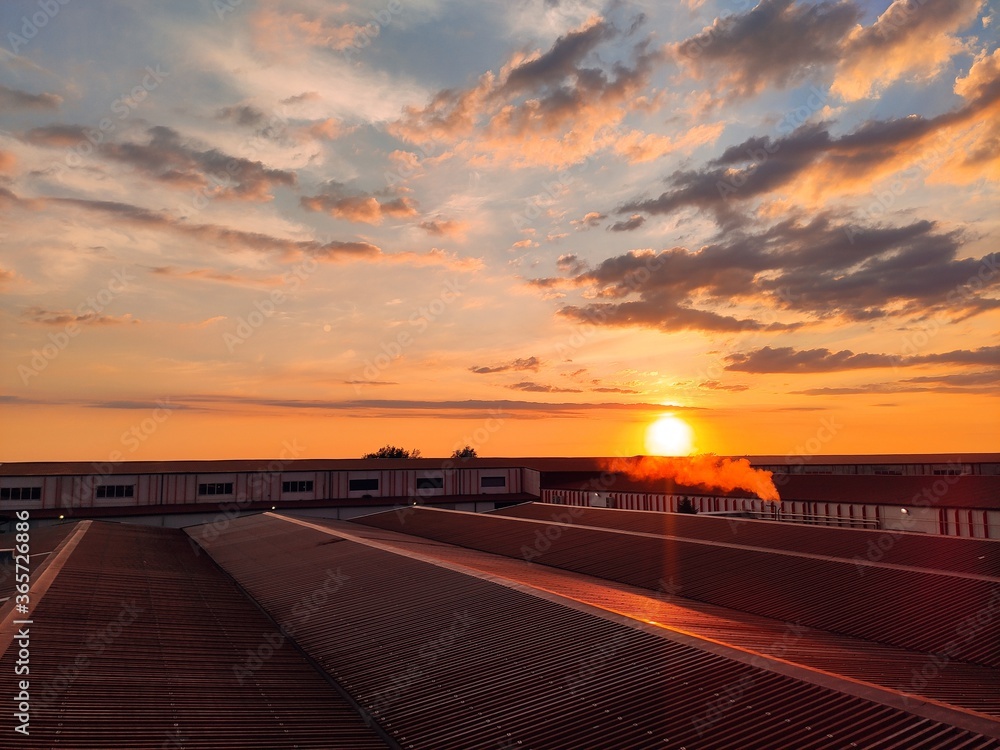 Cloudy sunset over factory roof