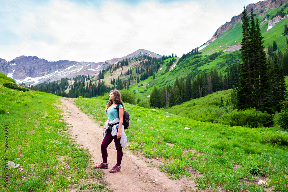 Albion Basin, Utah summer with woman standing on steep road path landscape view on meadows trail to Cecret lake in Wasatch mountains