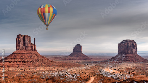 Colorful hot air balloon over majestic monument valley covered in snow