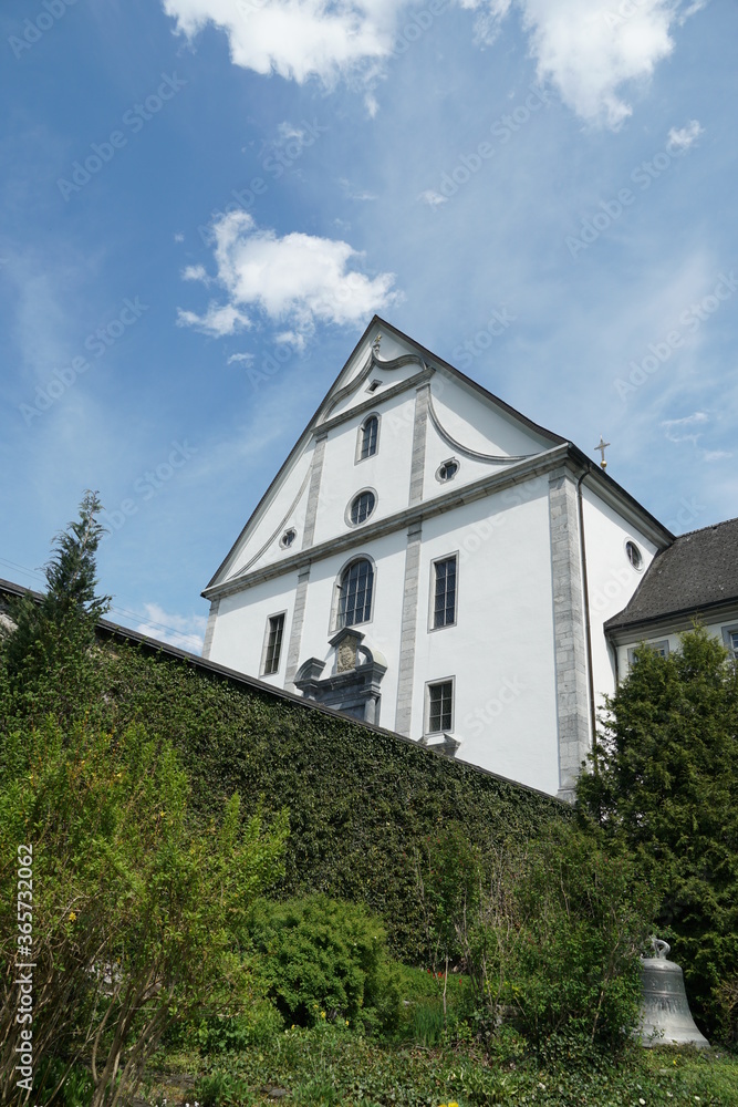 Facade of church belonging to monastery from behind in Engelberg, Switzerland. The wall, covered with plants, surrounding terrain of the monastery.