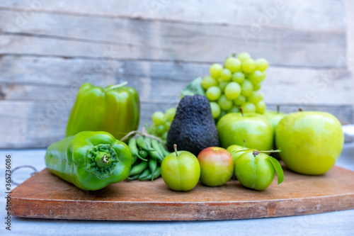 Green vegetables and fruits on a chopping board