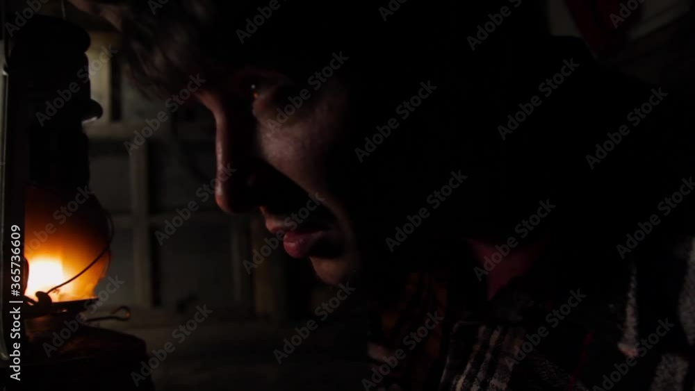 A young man in an old house lights a path with a kerosene lamp A young man in an old house lights a path with a kerosene lamp