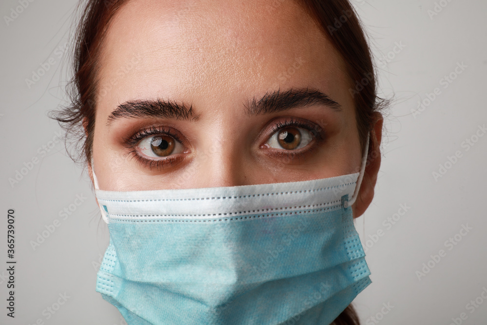 Close-up of young brunette woman using medical mask. Stay home. Pandemic situation. Close-up of young brunette woman using medical mask. Stay home. Pandemic situation.