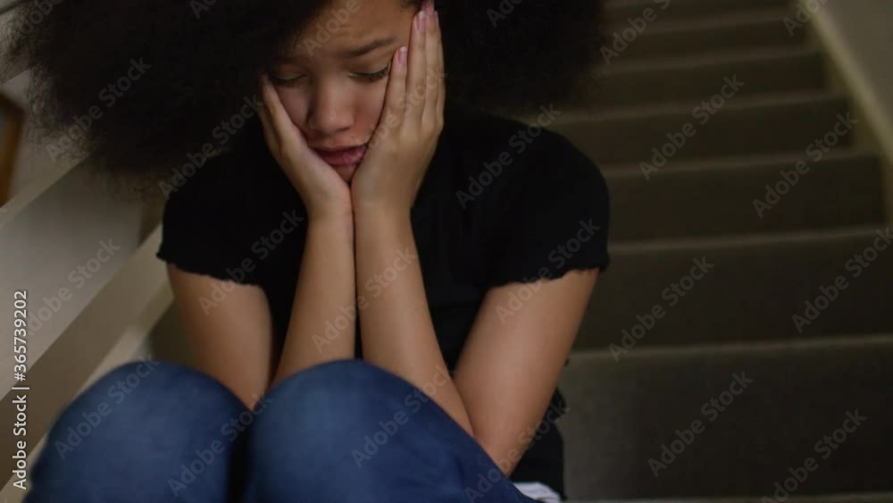 Beautiful young girl sitting on a staircase feeling very anxious as she