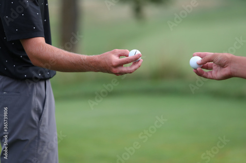 Tournament golfers show each other the type of ball they are playing. © Ron Alvey