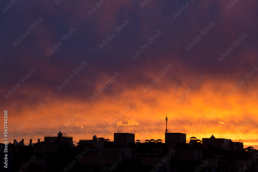 Pink orange purple sunset over the city. Multicolored sky and black silhouette tall buildings of the metropolis
