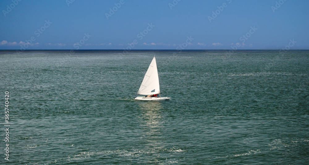 Desporto com barco á vela no mar em dia quente de verão com céu em cor azul intenso, um barco