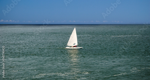 Desporto com barco á vela no mar em dia quente de verão com céu em cor azul intenso, um barco