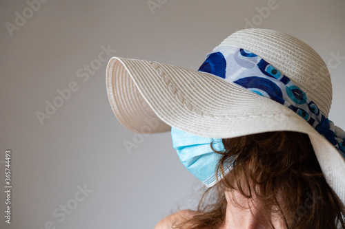 beach holiday during coronavirus woman with hat and medical mask