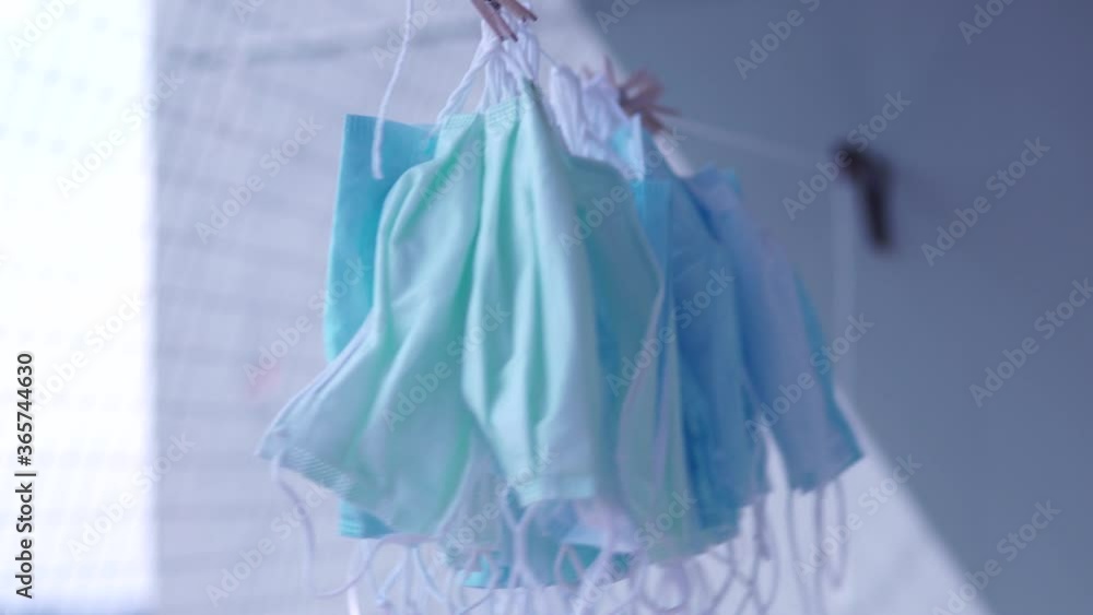 Hanging disposable masks hanging outside for disinfection and sterilization. Concept of new normal, mandatory face masks bylaw in public indoor settings. Reuse, shortage and price gouging concept. COV Hanging disposable masks hanging outside for disinfection and sterilization. Concept of new normal, mandatory face masks bylaw in public indoor settings. Reuse, shortage and price gouging concept. COV