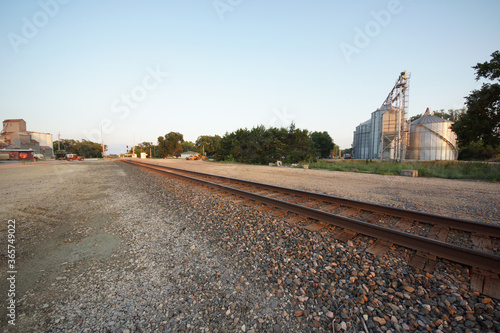 A railroad through a small town in the Kansas countryside with grain elevators, mills and silos.