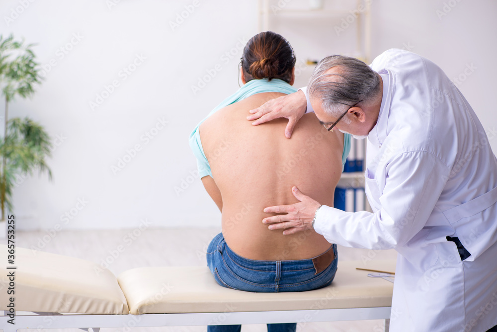 Fototapeta premium Young back injured man visiting experienced male doctor