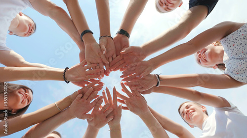 Cheerful friendly friends align their hands in the center. Teamwork concept.