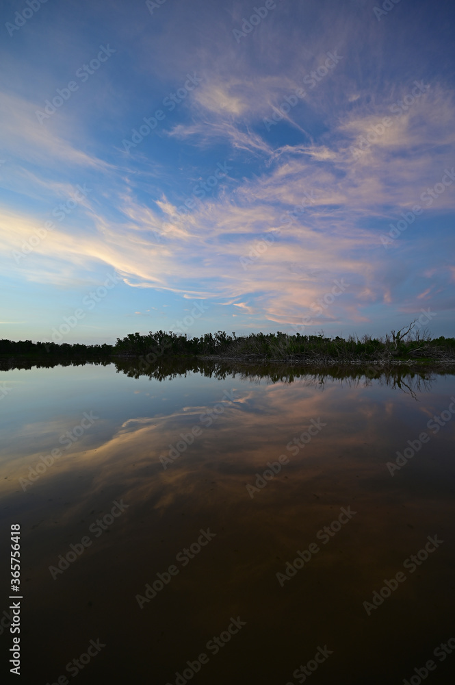 Brilliant colorful clouds in twilight reflected on calm water of Eco Pond in Everglades National Park, Florida on summer evening.